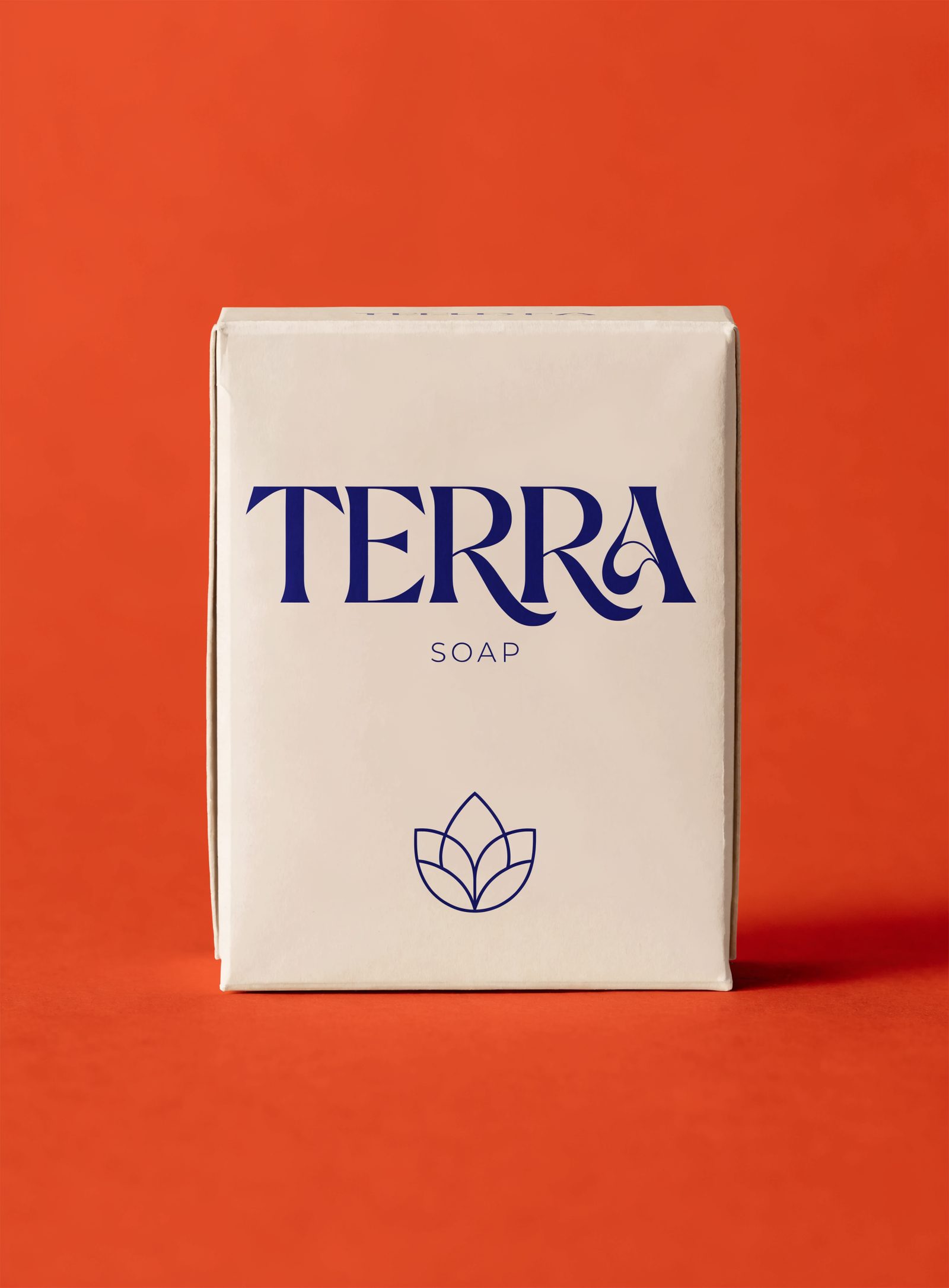 Cream TERRA SOAP packaging with crisp navy typography against an orange backdrop.