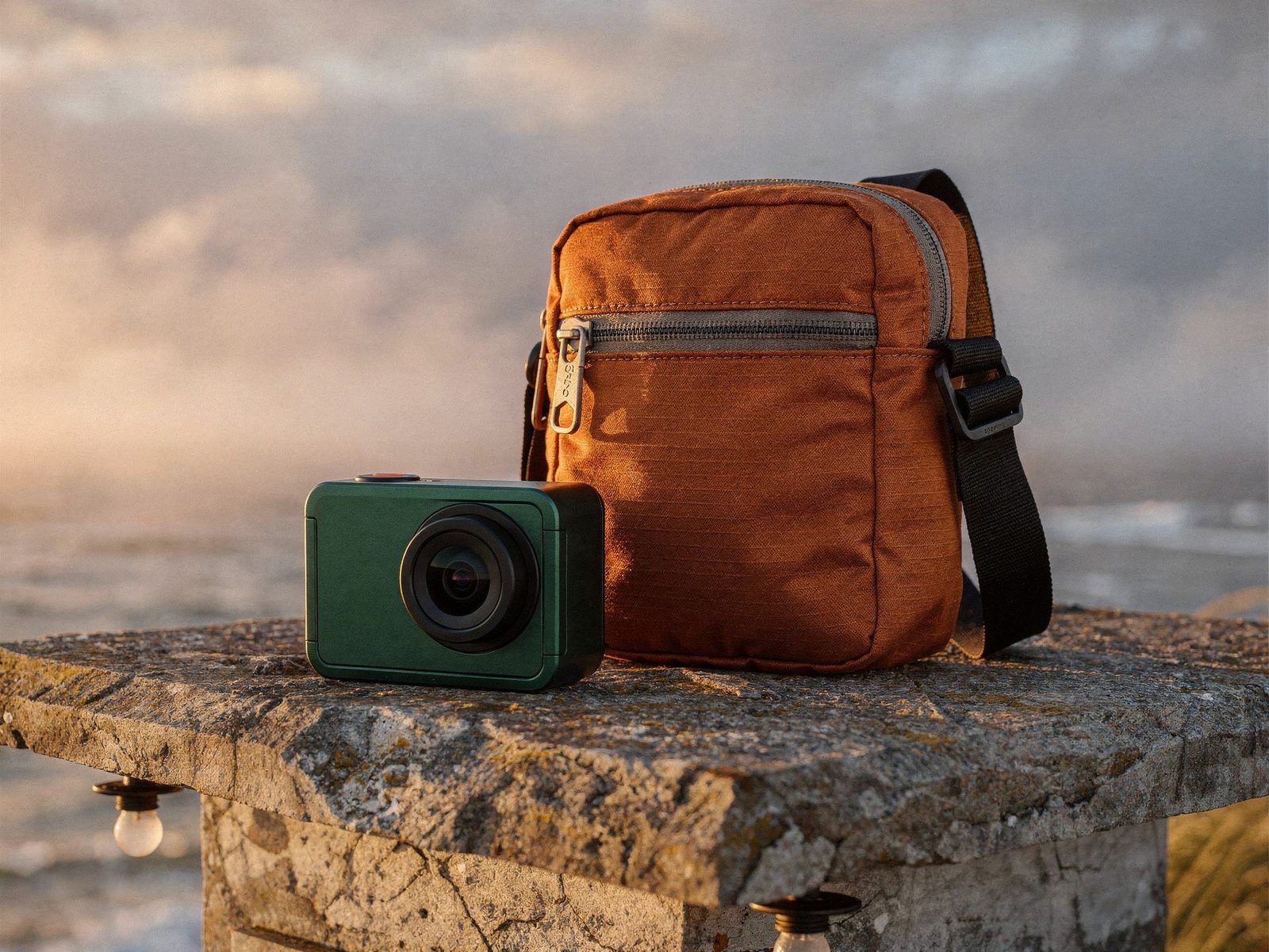 FLUX.2 Max outdoor campaign combining three dedicated FLUX.2 references: a green camera, an orange sling bag and a coastal shelter