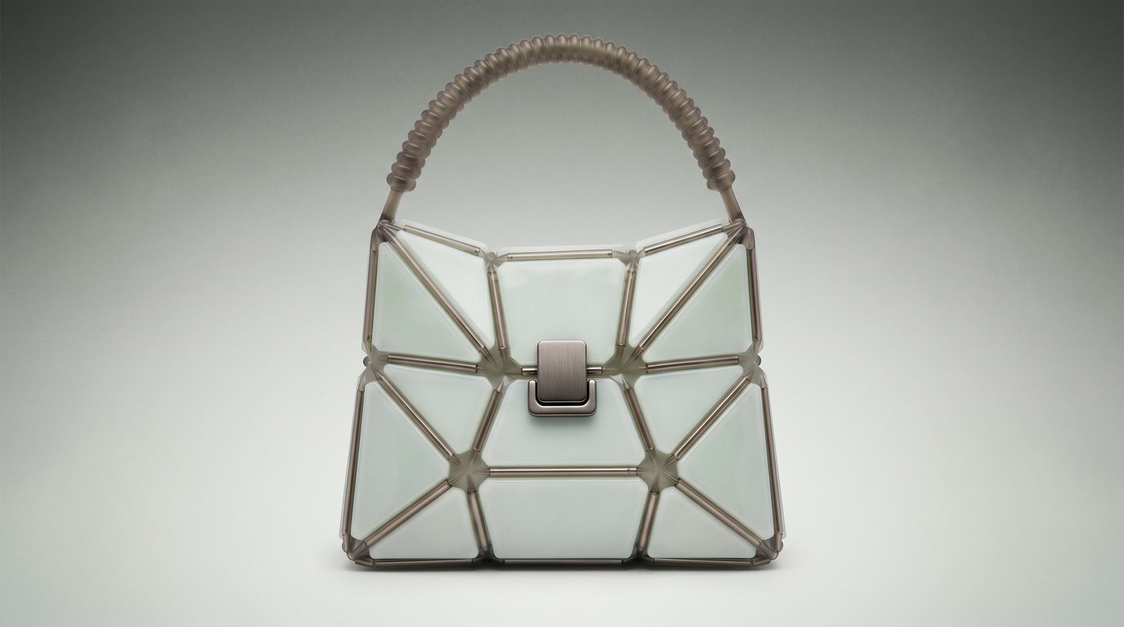 Geometric handbag concept with translucent panels and a woven handle against a muted studio background.