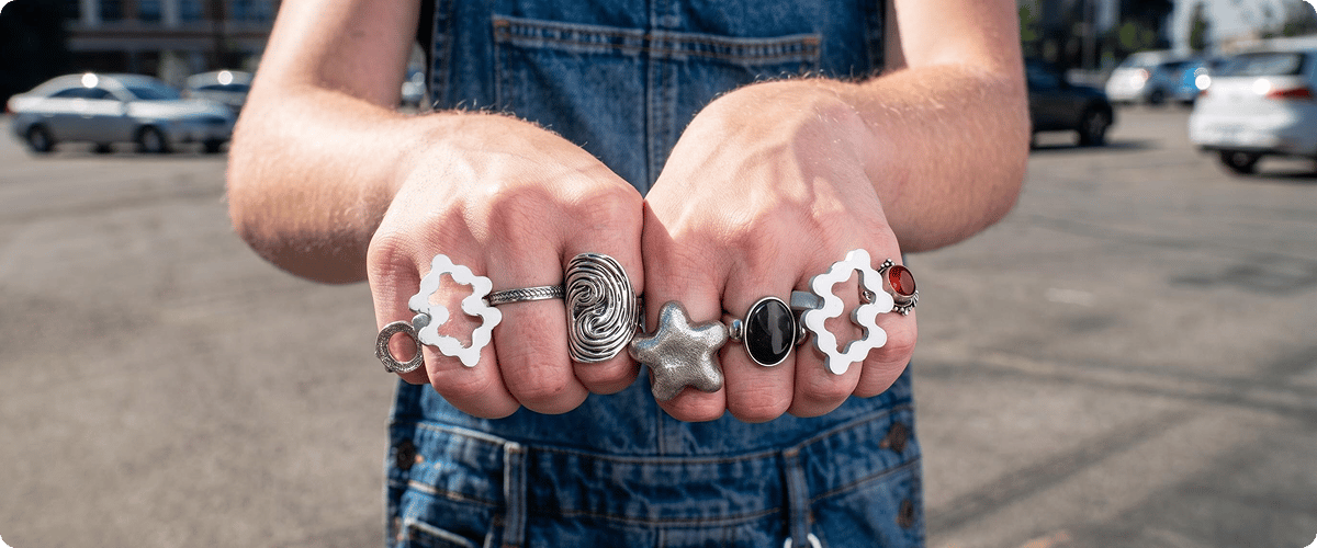 Two hands making fists joined together wearing silver chunky jewelry