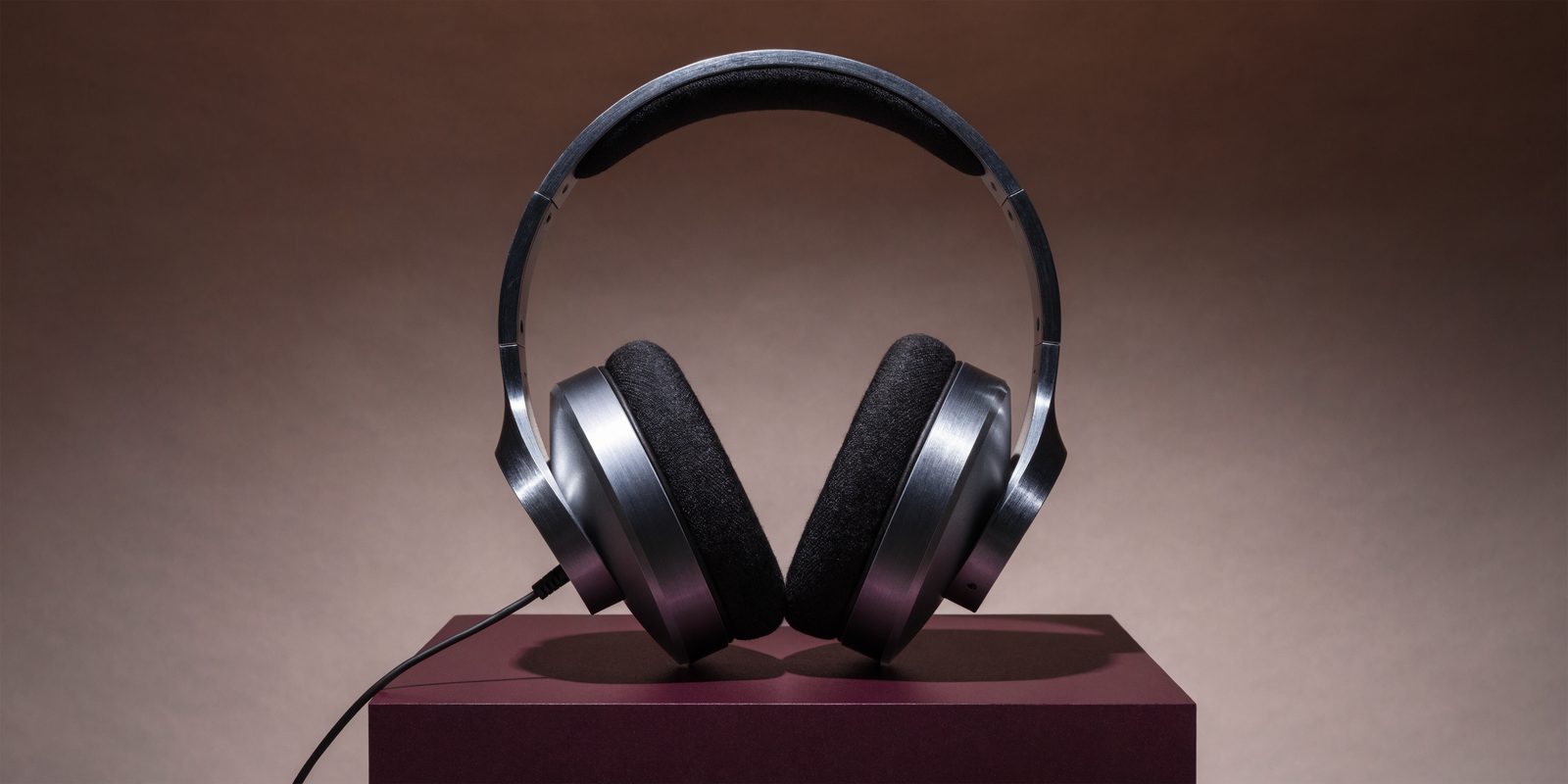 Black studio headphones on a burgundy pedestal.
