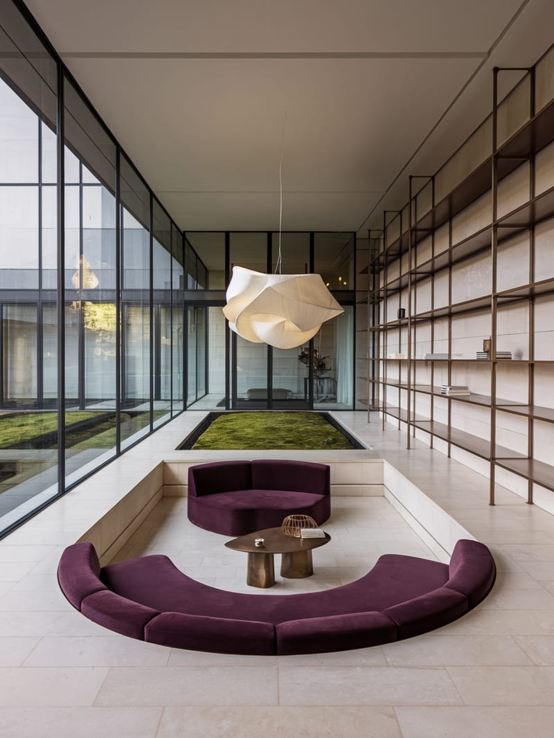 Modern glass interior with a plum conversation pit and sculptural pendant light.
