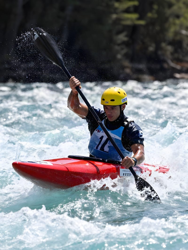 Kayaker in a red boat amid sunlit whitewater and suspended spray, upscaled by ESRGAN.