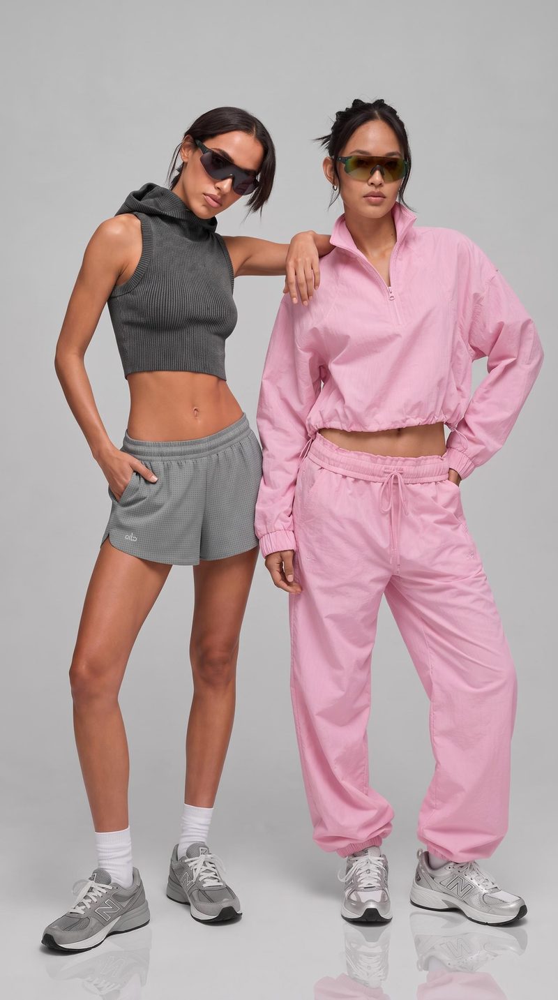Fashion editorial concept with two women in gray and pink casual outfits against a neutral background.