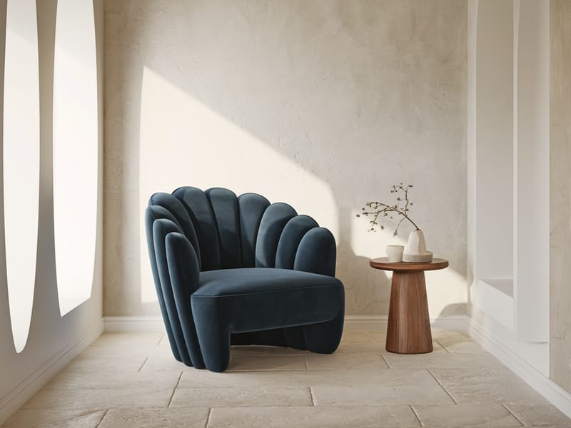 Deep blue sculptural lounge chair isolated in a neutral limestone interior.