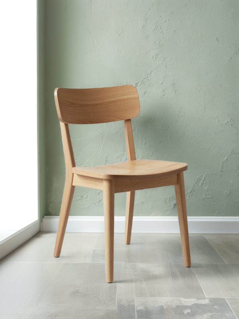 Minimalist oak chair staged against lichen-green plaster.