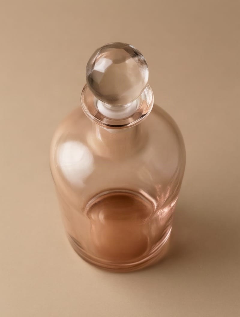Rose glass decanter seen from an elevated viewpoint, with its stopper, shoulders and refracted base visible.