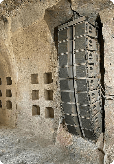 A stack of speakers embedded within a rocky cave wall